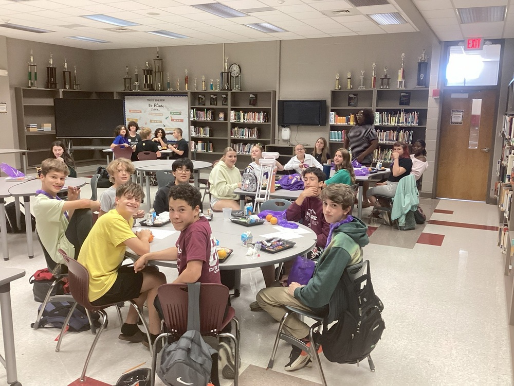 A group of students sitting at the tables in the library eating lunch  to celebrate puprle up day