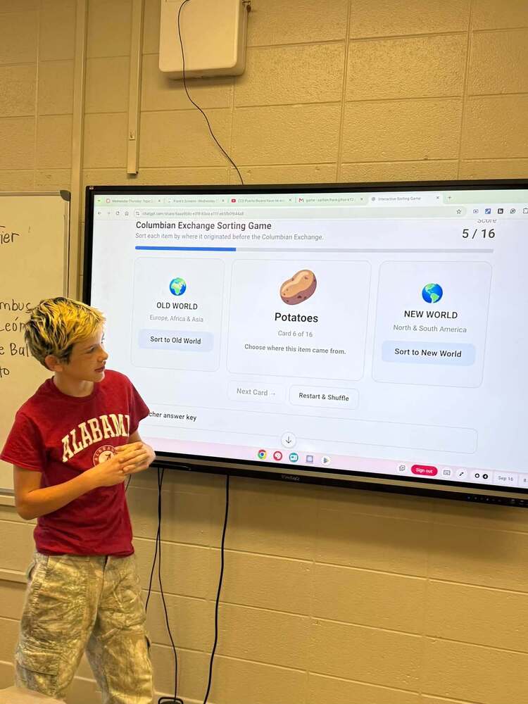 Student standing in front of large screen in Social Studies classroom
