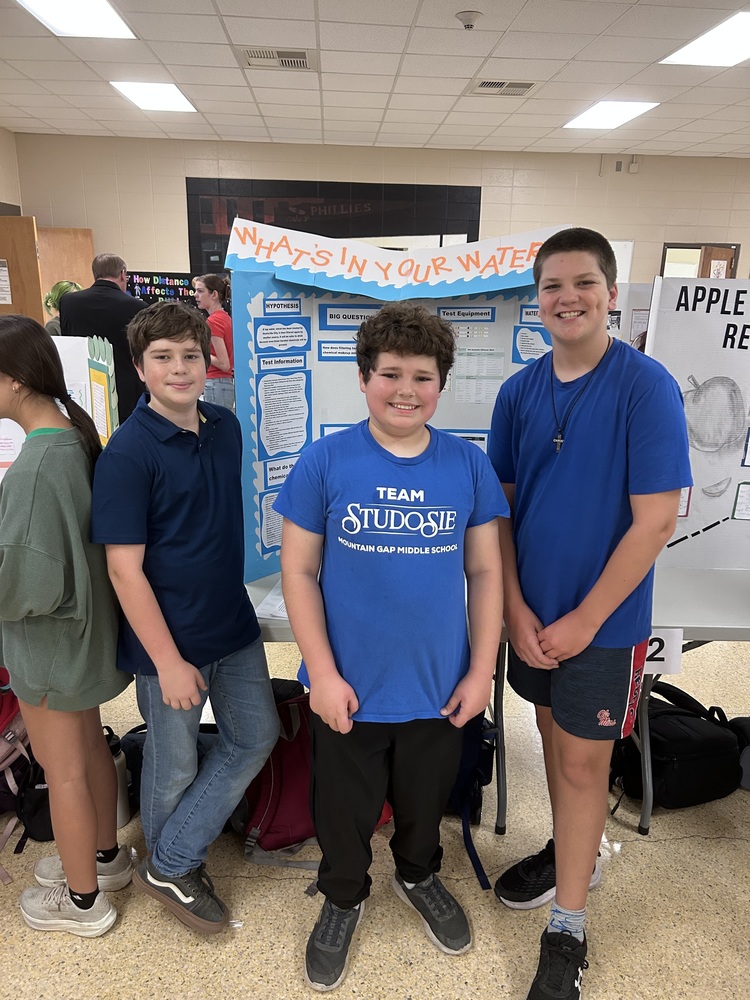 Three Students Standing in front of their project at the science fair