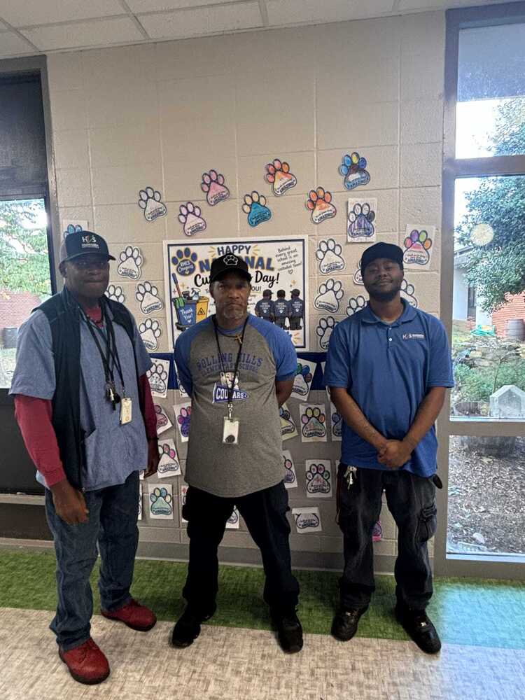 Custodians stand near a wall decorated with hadwritten student notes.