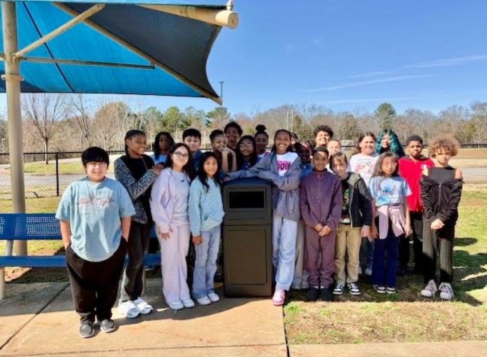Students standing around the trashcan that they had installed on the playground