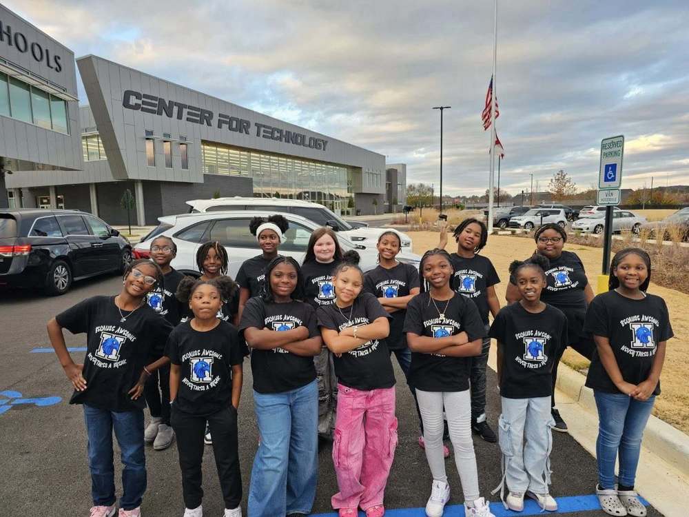 Students stand together outside the Huntsville Center of Technology, smiling and posing for a group photo.