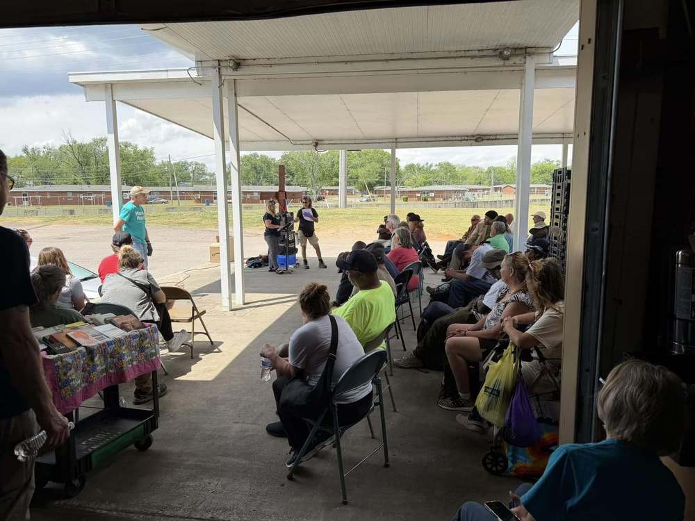 people sitting listening to a sermon prior to eating at shelter