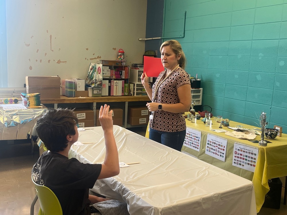 Teacher Sabrina Priest stands in front of the room, showing students how to make an Origami crane. 