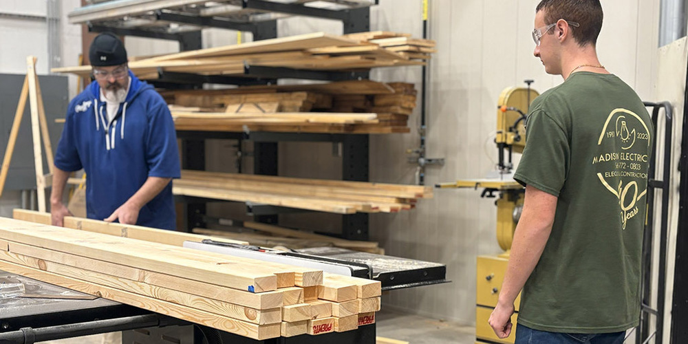 Teacher cutting board while student prepares to assist
