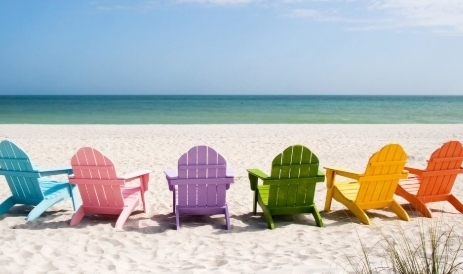 blue, pink, purple, green, yellow, and orange beach chair sitting on the beach facing the ocean