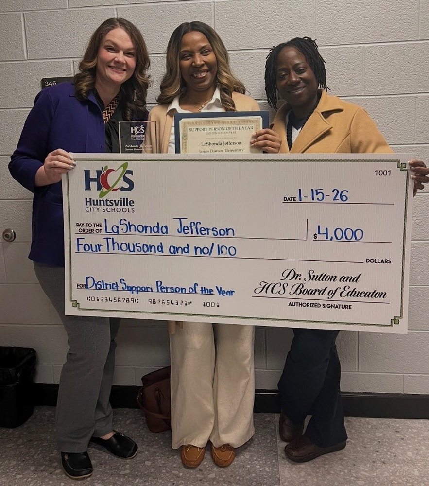 3 women stand with a large check from HCS made out to LaShonda Jefferson for four thousand dollars.