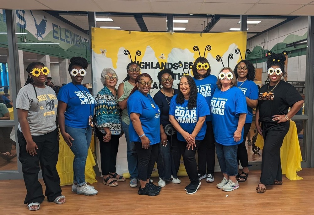 Highlands Elementary Staff poses for a picture to celebrate ESOL night wearing silly flower glasses to match the theme "Highlands' ESOL is the place to bee". 