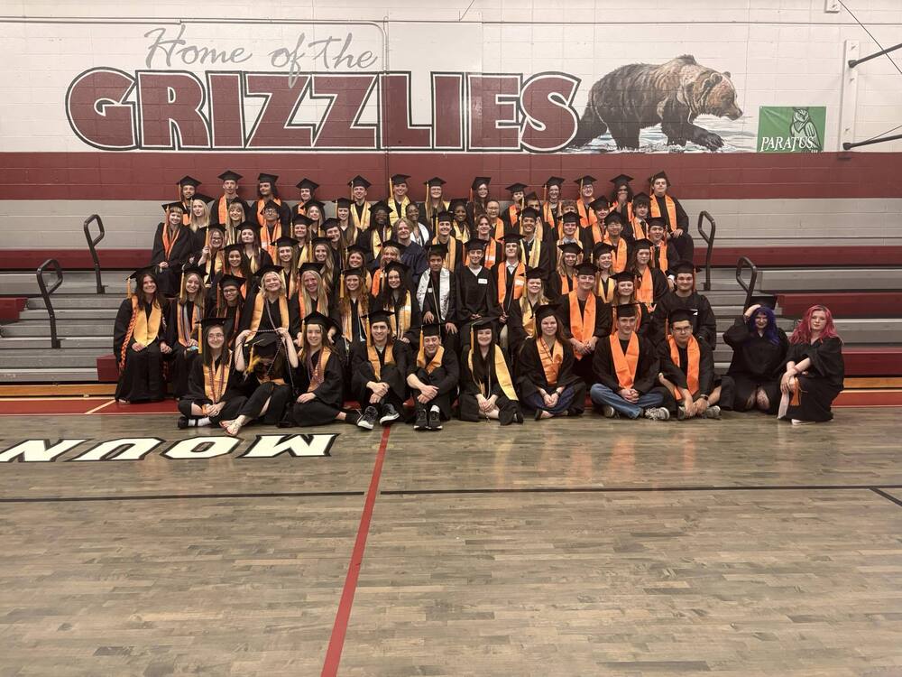 Seniors that returned to Mountain Gap sitting on bleachers for a group picture with Home of the Grizzlies written on the wall behind them