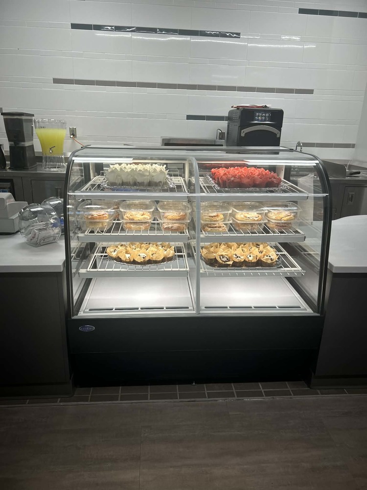 Culinary display case full of muffins and cinnamon rolls 