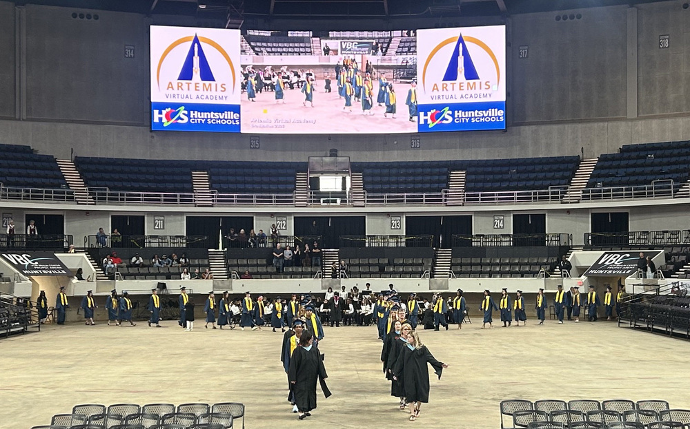 Teachers and seniors, dressed in their graduation regalia, walk into the Von Braun Center. 