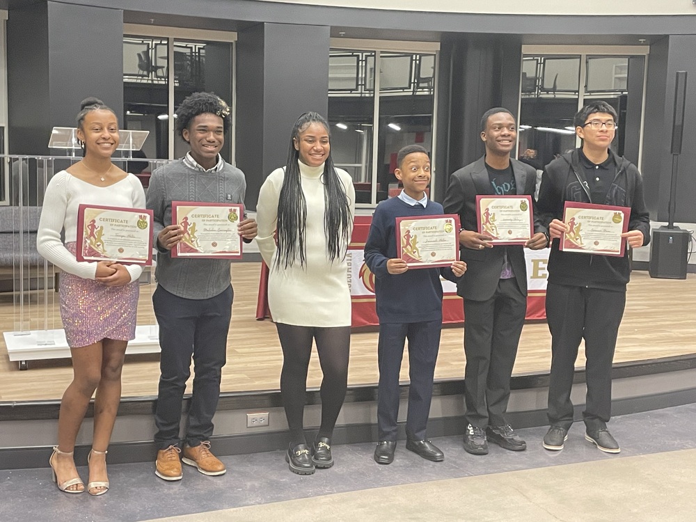 5 Cross Country Athletes with their Coach holding up certificates posing for picture