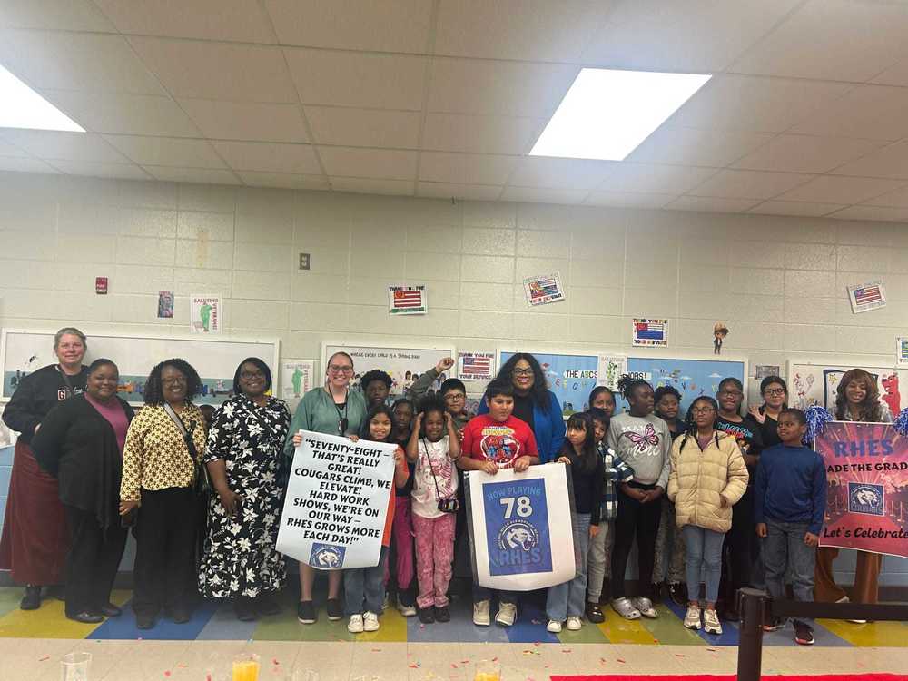 Staff and students of Rolling Hills Elementary School holding colorful signs celebrating their state report card grade, smiling and posing together