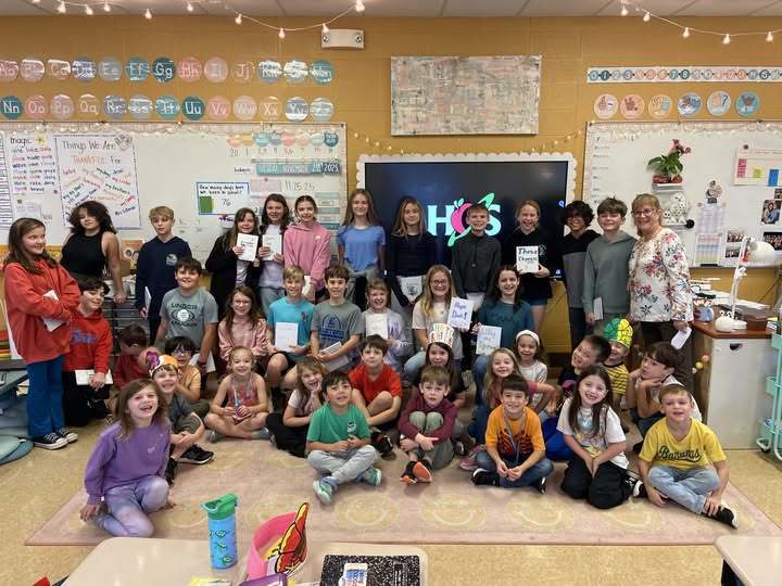 Ms. Byar's and Ms. Rhonemu's students sitting and standing in classroom  with self-created books.