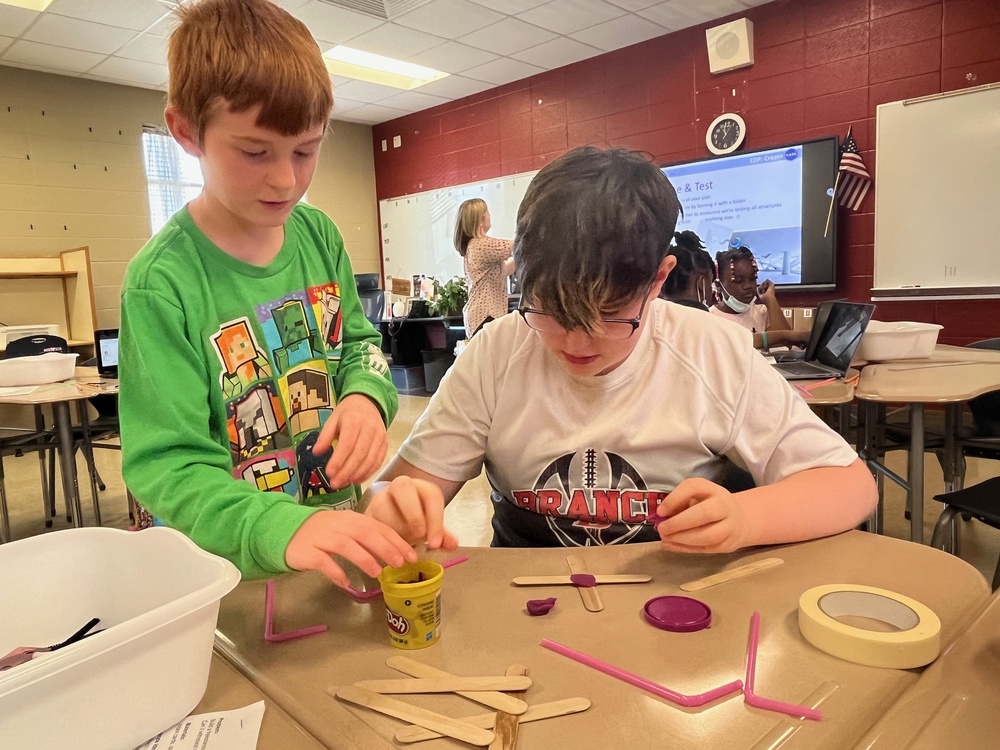 Two male students work together to build a tower
