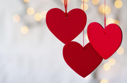 red hearts hanging from red string and with lights behind them 