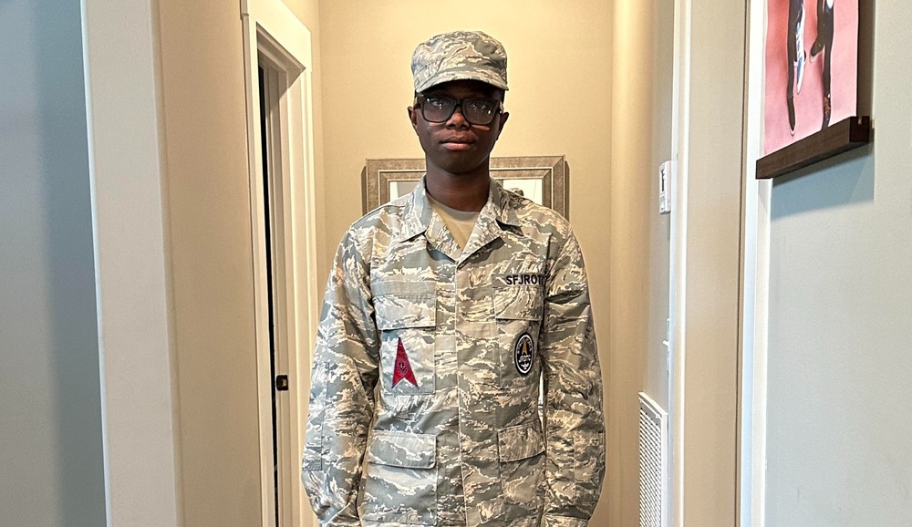Young man in uniform stands at attention.