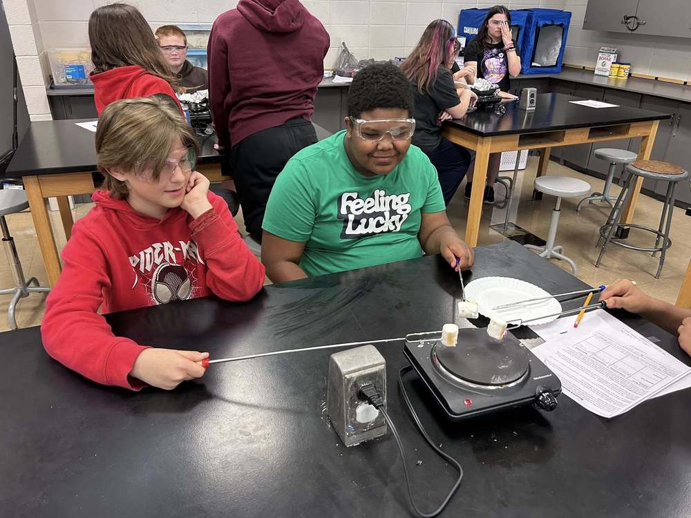 Two 8th grade students roasting marshmallows in their thermal energy lab