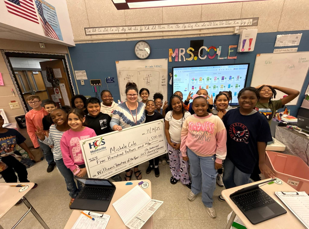 Teacher of the year Mrs. Cole holding a giant check in her classroom with students