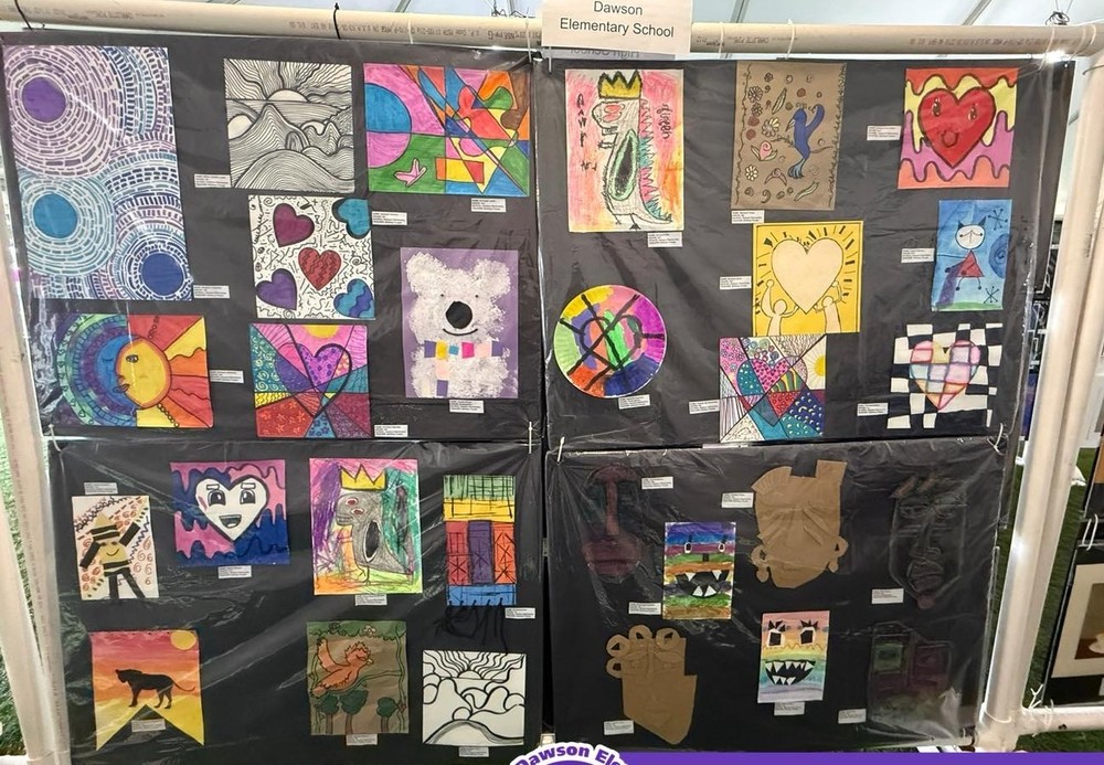 A collection of various artwork is hanging on a black backgrop.  