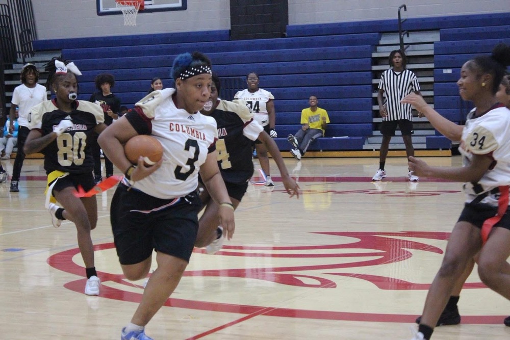 Girls in gym at Columbia with Columbia shirts on playing flag football during Powderpuff game in gym