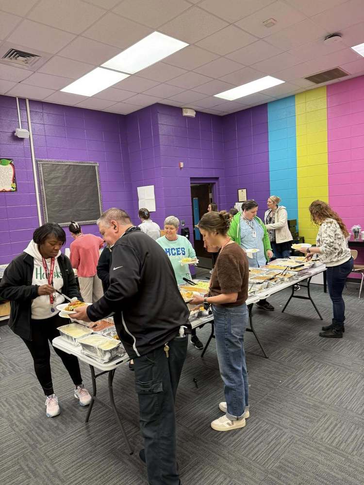 Teachers being served lunch in a room with colorful walls.