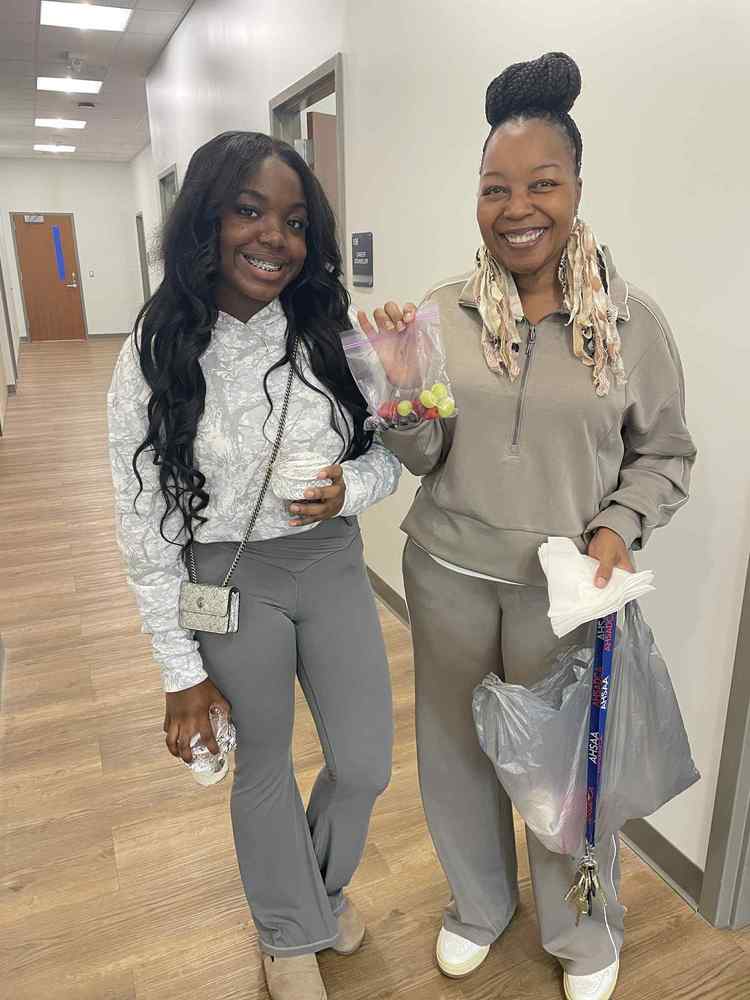 Ms. Johnson, cosmetology teacher and student posing with yogurt bowls and fruits in a bag.