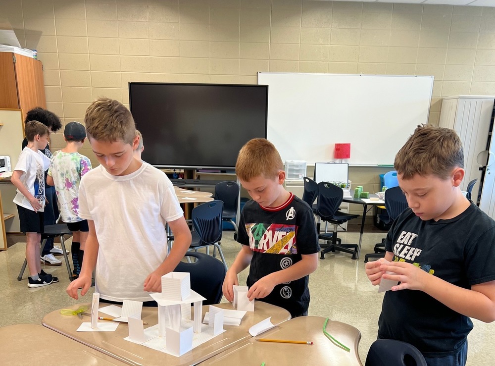 Three elementary students build an tour with index cards.