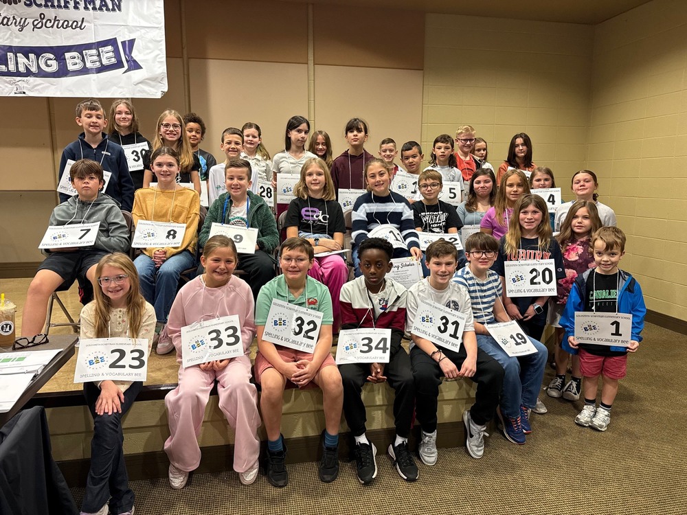 Students sit holding up their numbers after they competed in the spelling bee.