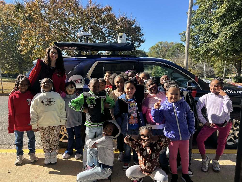 Meteorologist Grace Anello smiling and posing with a group of 2nd grade students
