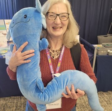 Michelle Barnett hugging on a stuffed animal at a conference