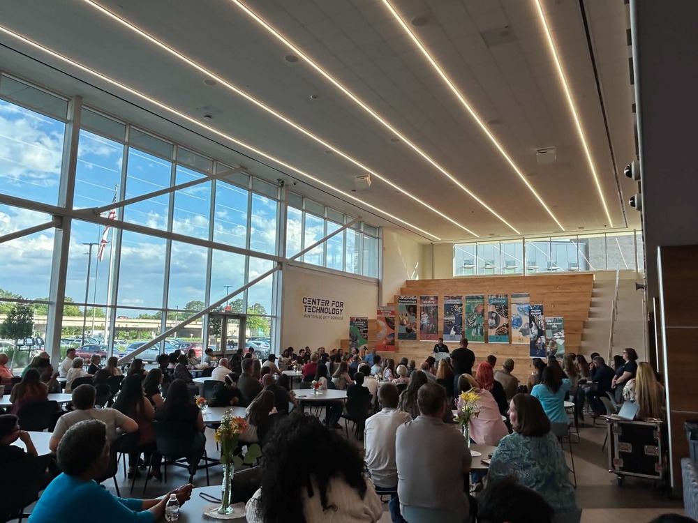 Inside of the Center for Technology with a room full of parents and students sitting at tables facing the large staircase with banners representing each CTE program sitting on them