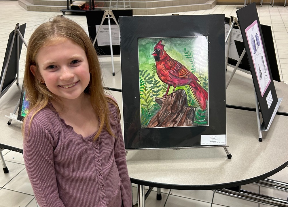Female student stands beside artwork of a cardinal.
