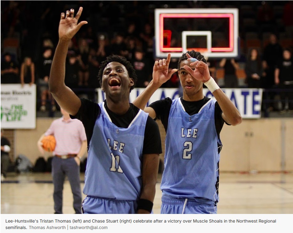 Lee-Huntsville players Tristan Thomas (left) and Chase Stuart (right) raise their hands in celebration on the court after a win, with the basket and spectators in the background.