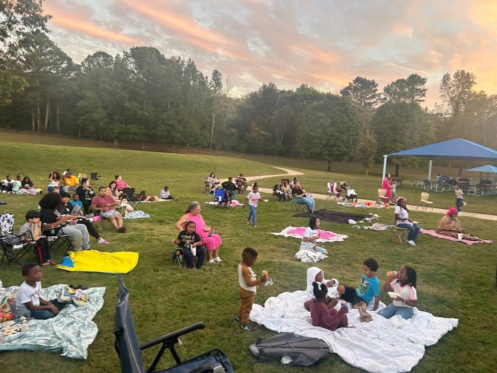 Parents, students, and families sitting outside on the lawn with blankets 