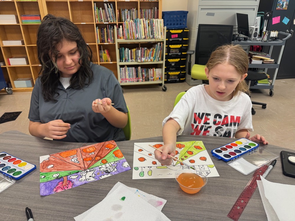 Two female students work on an art project in the school's library.