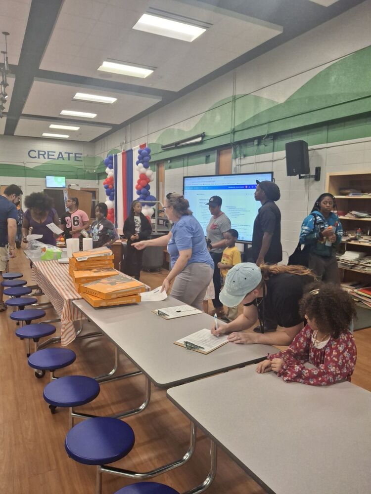 A group of students, families, and school staff gathered together in Highlands Elementary School's cafeteria for a school community event featuring food, conversation, and activities.