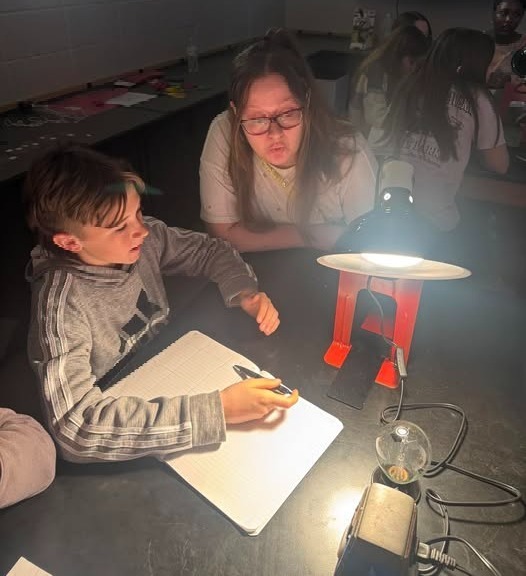 Ms. McBride watching a student do the experiment at the lab table