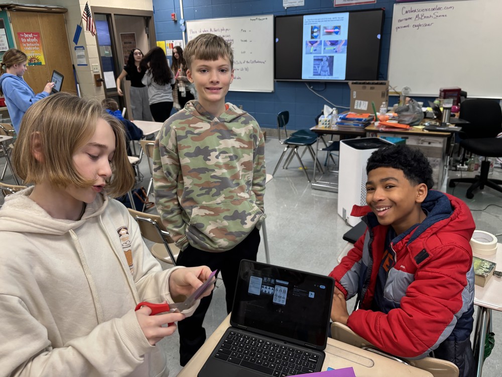 Three boy students working together on their rocket project in science class.