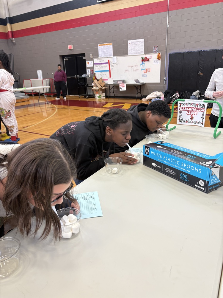 Three students playing marshmallow scoop at the Minute to Win It PBIS celebration.