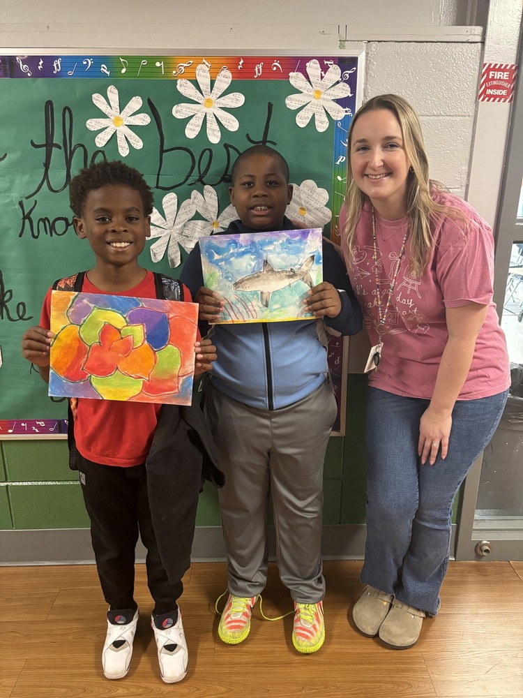 Art teacher and students post for the photo holding their art work