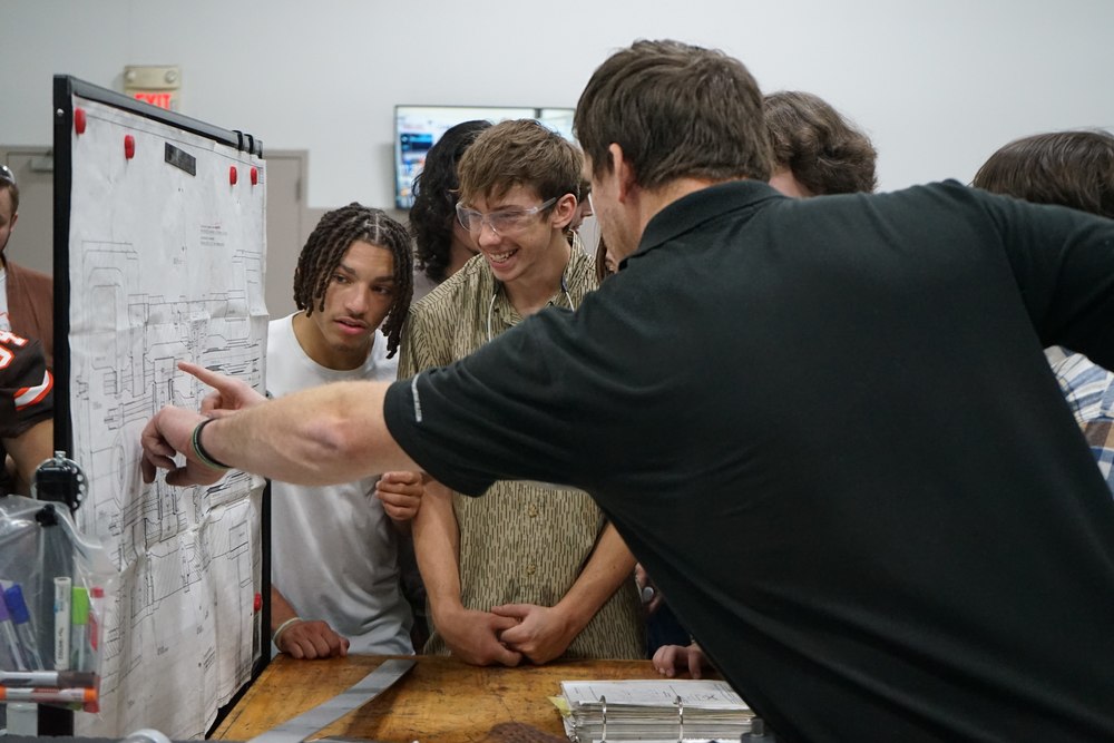 Bruderer employee pointing out machine diagrams to welding and precision machining students