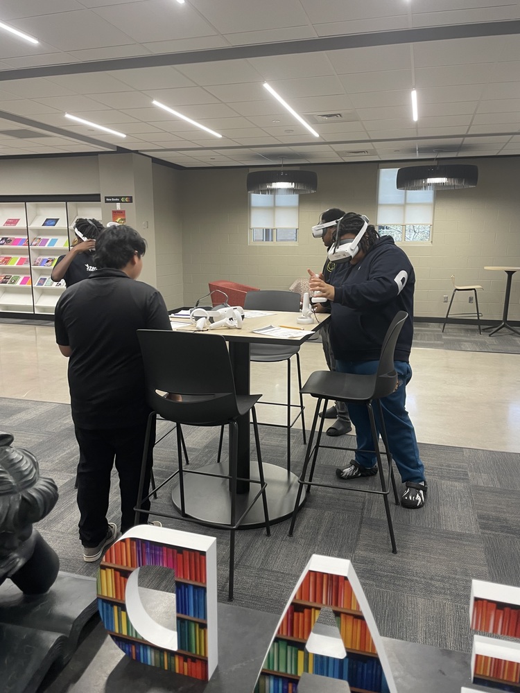 Four students in the library standing using VR headsets with lesson about DNA structure
