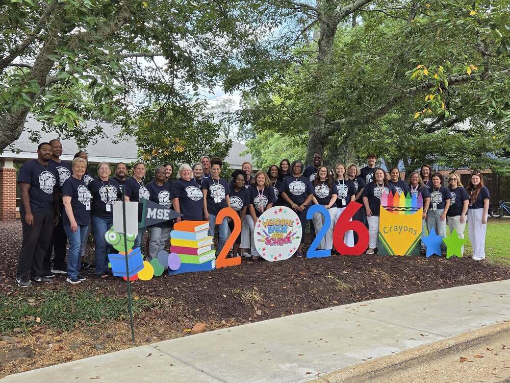 group photo of faculty outside in matching navy shirts with MSE logo on front