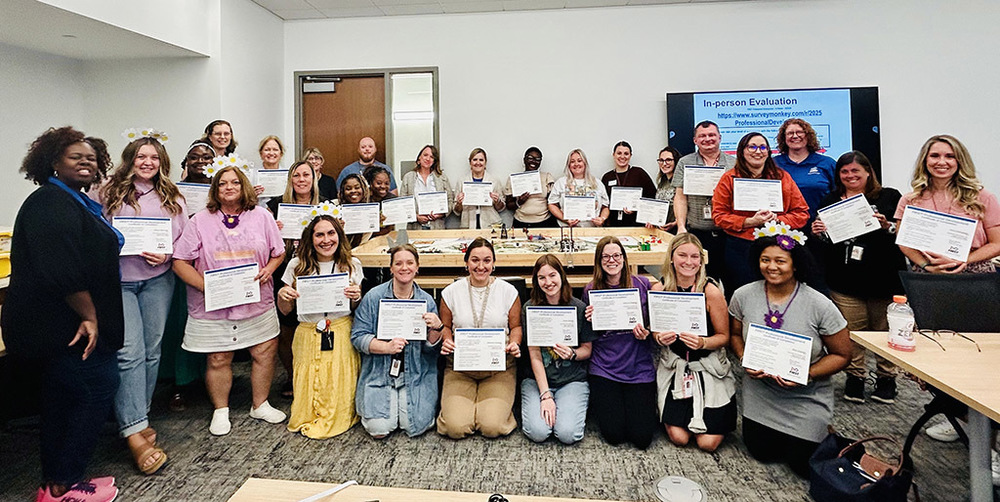 Elementary Teachers pose holding their completion certificates for robotics training
