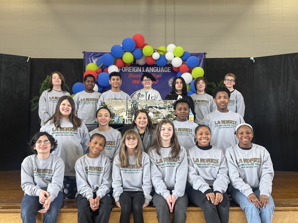 Future City students gather together, smiling for a photo in front of a large, vibrant ASFL banner.