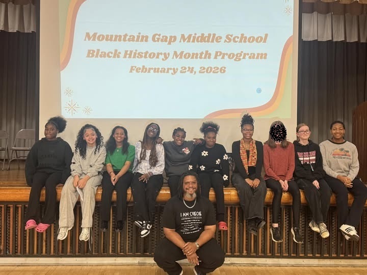 Students who participated in the black history program sitting on the stage with our guest speaker, Mr. Mason