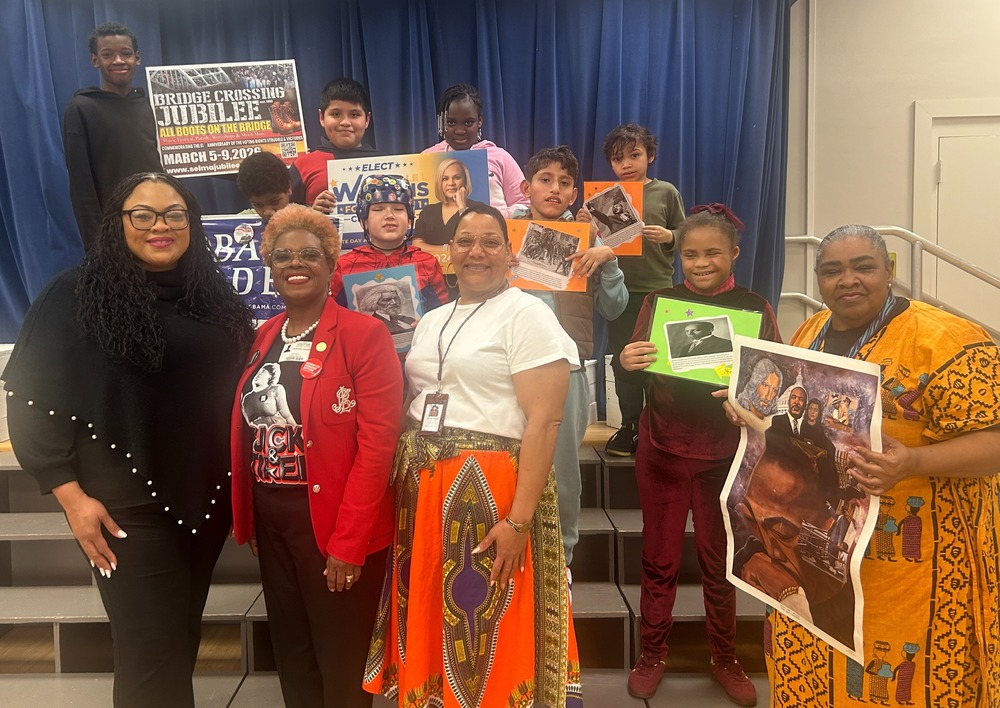 Rolling Hills Elementary students and staff pose on stage holding Black History posters during a school program.