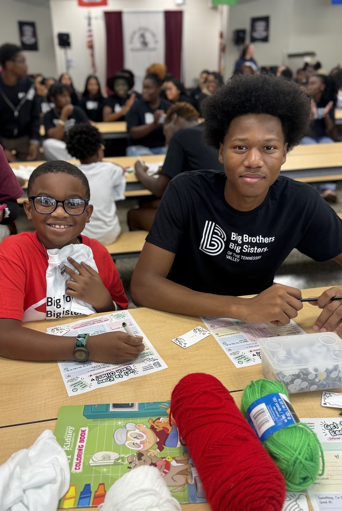 2 boys, 1 in red and 1 in black sitting in table