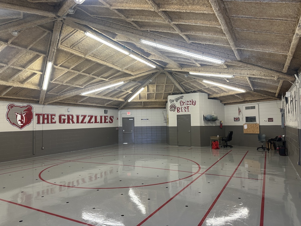 Gym Pod freshly painteed with a Grizzliy bear on the wall  and with words. The floor is freshly painted gray with red lines.